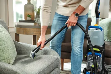Using tool on hose on end of TurboClean DualPro Pet Carpet Cleaner to deep clean stain on upholstery.