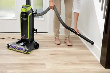 Using Hose with Dusting Brush to vacuum baseboards.
