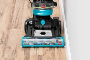 CleanView Swivel Rewind Pet Vacuum vacuuming hard flooring along baseboards.