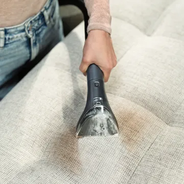 Using Hose on Portable Carpet Cleaner with tough stain tool to clean stain on cushion.