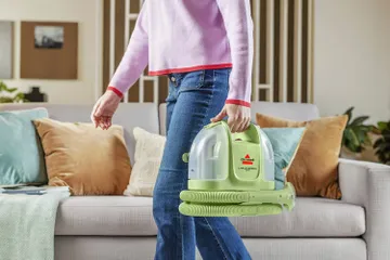 Little Green Mini Portable Carpet Cleaner being carried across living area