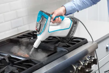 Using Hand Steamer with tool to steam kitchen stove.
