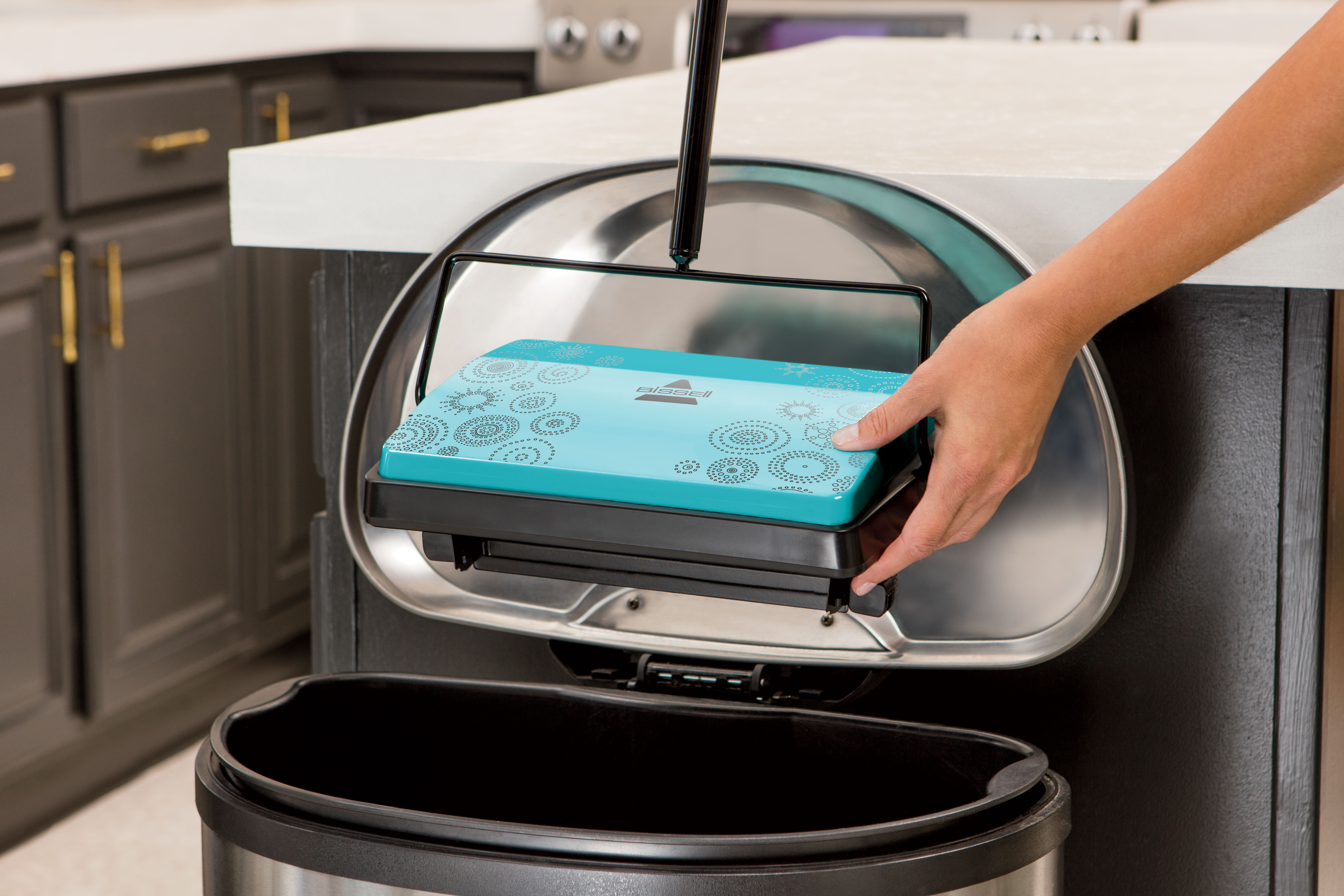 REFRESH Manual Sweeper’s Easy Empty dust bins being emptied into trash bin.