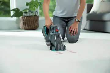 Portable deep cleaner cleaning stain off carpet.