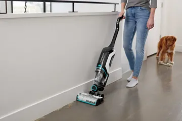 CrossWave Cordless Max Multi-Surface Wet Dry Vac vacuuming pet hair along baseboard.