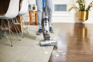 Man holding a bissell vacuum and cleaning his living room