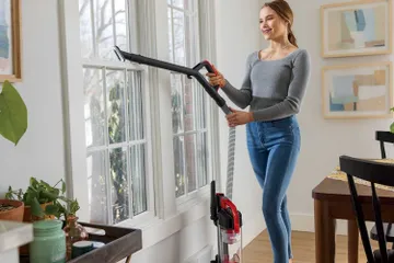 Using Hose with Dusting Brush to vacuum above flooring.