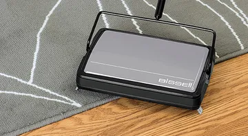 Sturdy Sweep™ Carpet & Manual Sweeper cleaning on area rug and hard flooring.