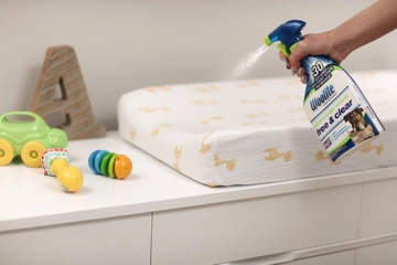 Woolite® Free & Clear Pet Stain & Odor Remover Pretreat being sprayed on baby bed.