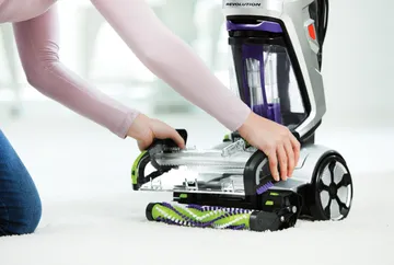 Removing Brush Roll Cover from foot of carpet cleaner.