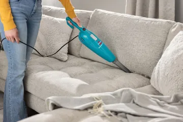 FeatherWeight Stick Vac vacuuming couch cushion with crevice tool