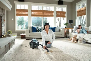 Using SpotClean Pro Portable Carpet Cleaner to clean stain on living room carpet.