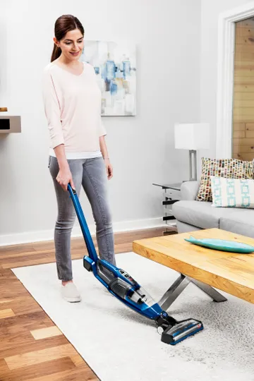 Using PowerSwift™ Ion Pet Cordless Sick Vac bending handle to vacuum under table.