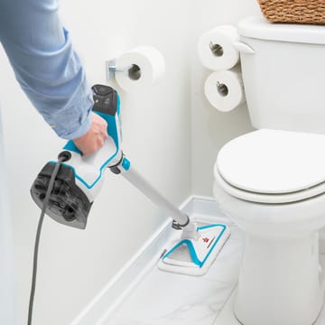 Using PowerFresh Slim 3-in-1 Steam Mop to mop tile flooring between wall and toilet in bathroom.