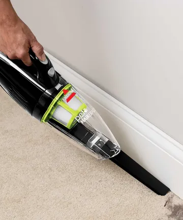 Using Crevice Tool to vacuum hair along baseboards