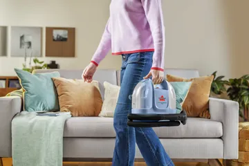 Little Green Mini Portable Carpet Cleaner being carried across living area