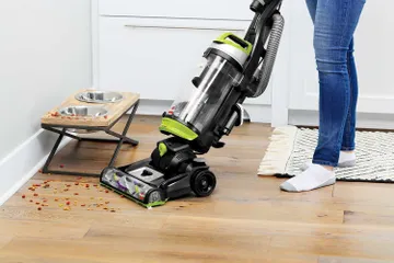 CleanView Swivel Pet Vacuum vacuuming dog food from hard flooring.