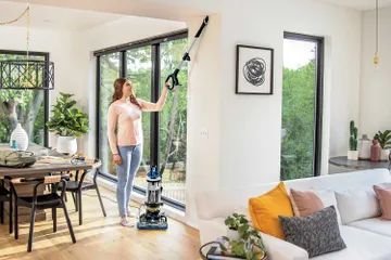 Using extension wand on hose to vacuum above flooring.