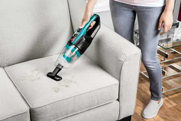 Using ReadyClean Cordless Stick Vac as a Hand Vac with combined crevice tool and dusting brush to vacuum couch cushion.