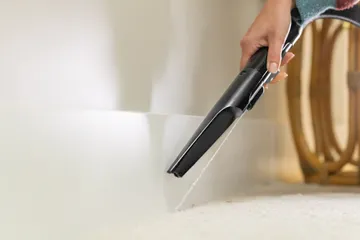 Using Spraying Crevice Tool to clean along baseboards.