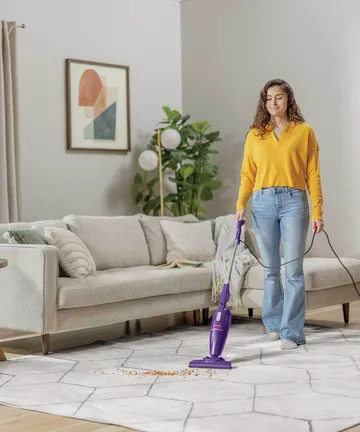 FeatherWeight Stick Vac vacuuming area rug.