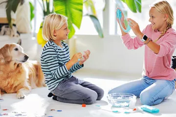 Kids playing with slime over carpet and dog nearby