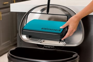 EasySweep Manual Sweeper being emptied with Easy Empty dirt bin